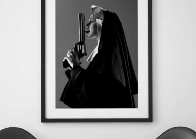 Artistic black and white portrait of a woman with a gun in a frame.