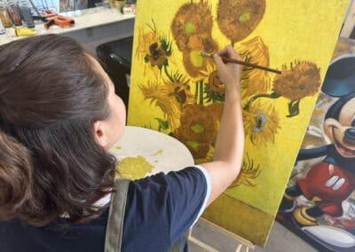 Sunflower canvas painting being created by an artist in a studio setting.